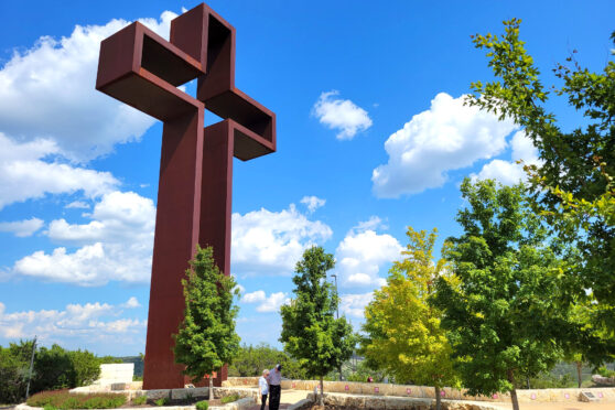 Large iron cross with tourist at base