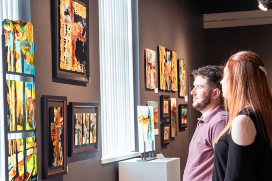 A man and a woman looking at art on a wall in a gallery setting