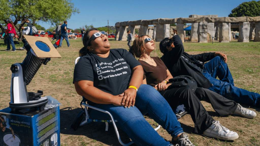 Visitors look at the eclipse with Stonehenge in Kerr County in the background 