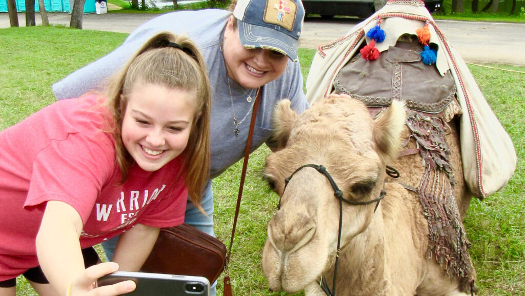 Two women taking a selfie with a camel
