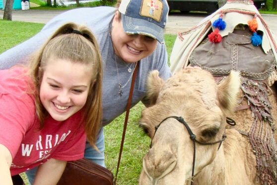 Two women taking a selfie with a camel