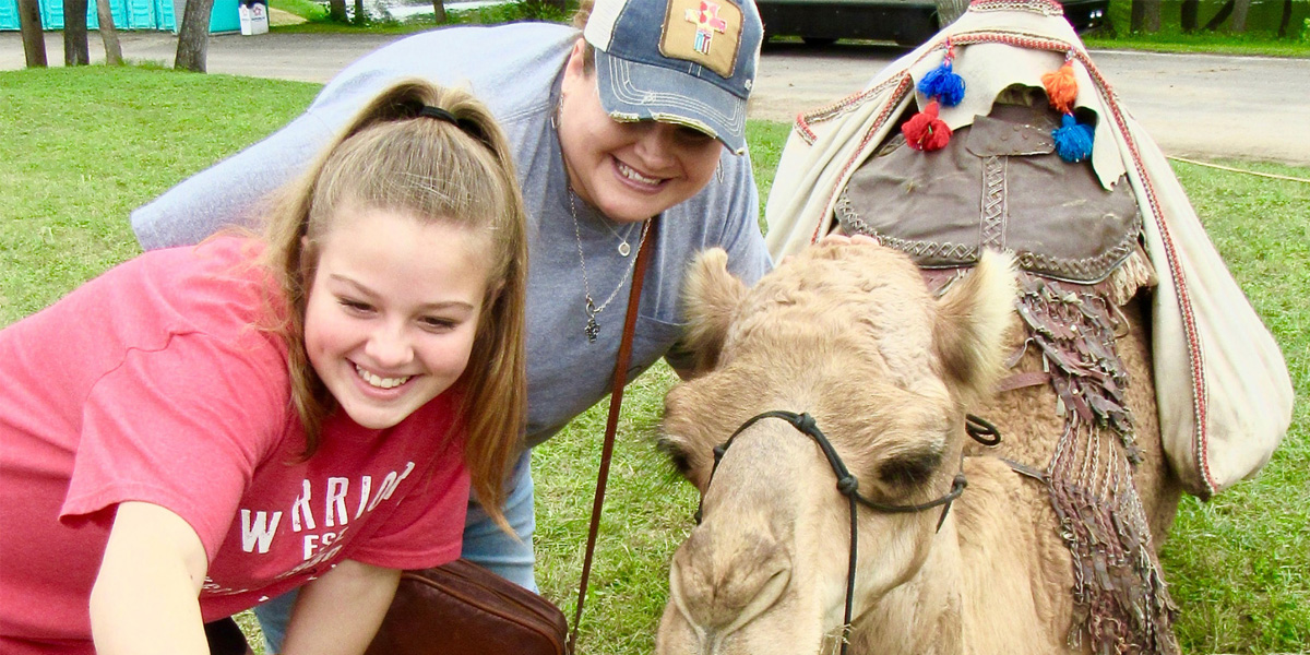 Two women taking a selfie with a camel