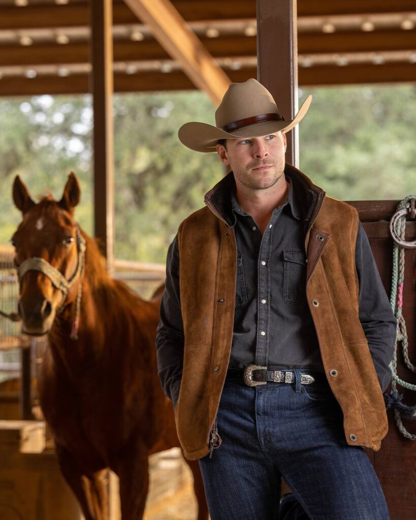 cowboy model wearing Clint Orms Engravers and Silversmiths designs with horse in stables