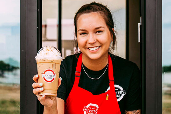 Scooter's Coffee employee holding coffee in drive thru