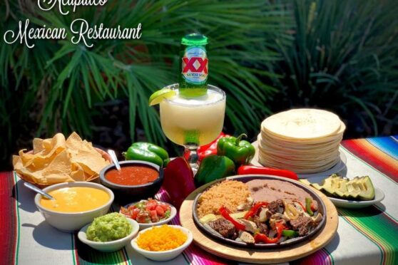 Mexican food display with fajitas, queso, salsa, sides and a margarita
