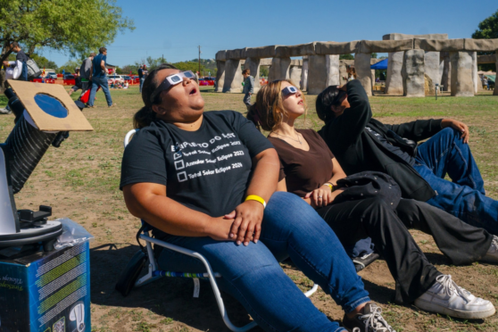 3 people in chairs looking at the solar eclipse with solar glasses