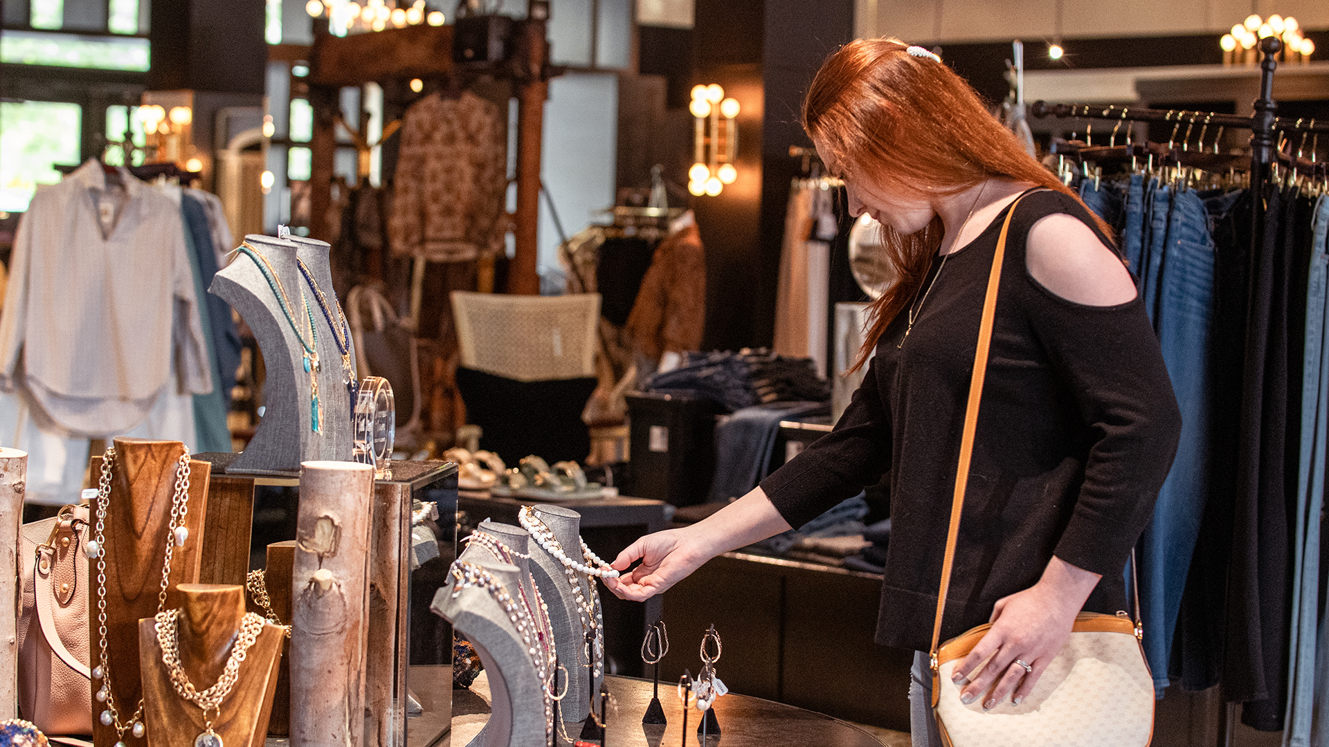Woman in black shirt and purse shopping for jewelry in a boutique store in downtown Kerrville