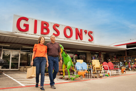Older couple walking in front of Gibson's Discount Store with merchandise for sale on the front patio of the store