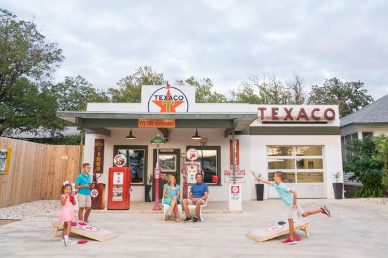 Old Texaco gas station converted into a short term stay property with a family hanging out in front