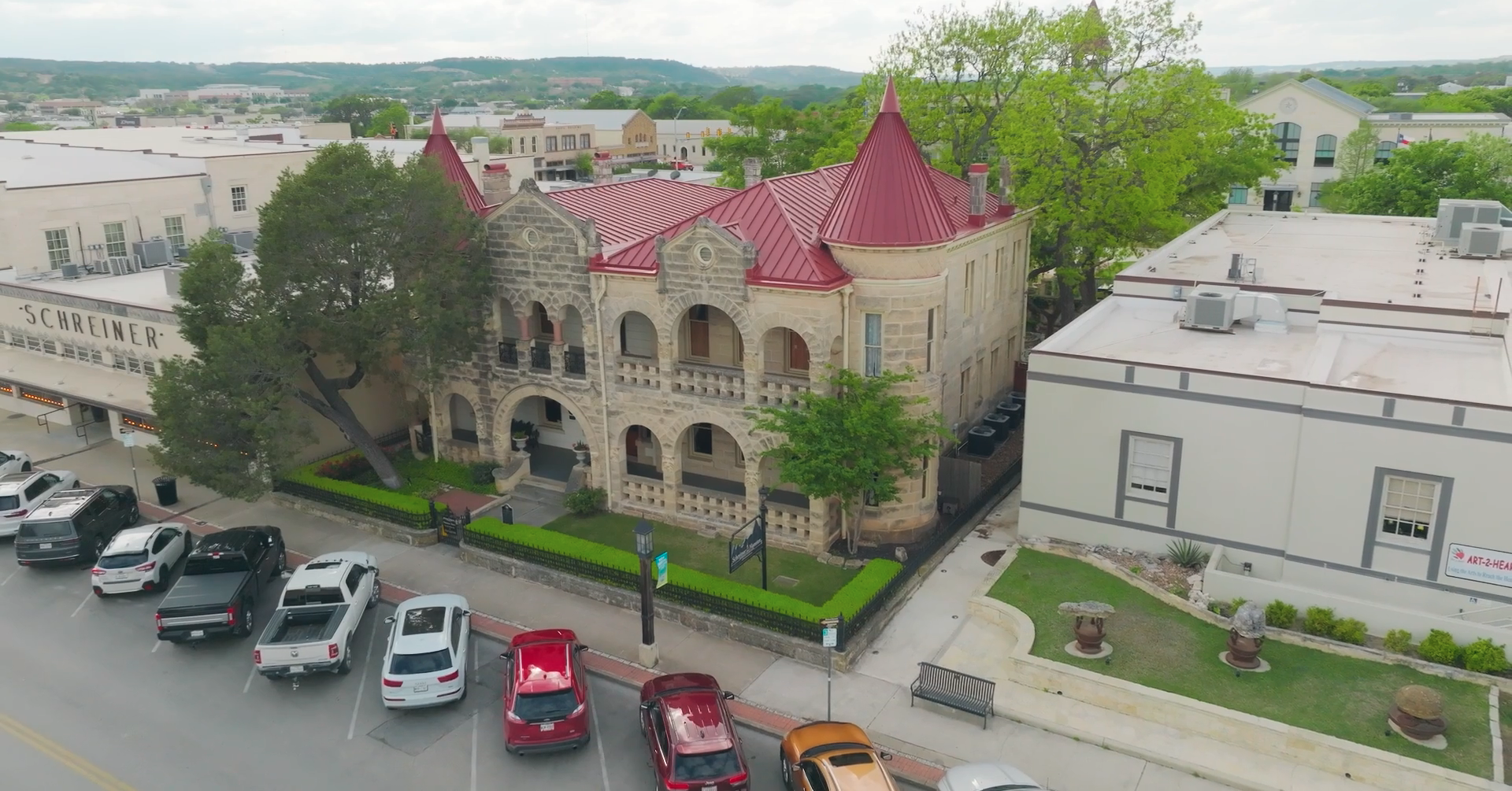 Aerial view of downtown Kerrville with cars parked along the downtown streets and a view of the historic Schreiner Mansion