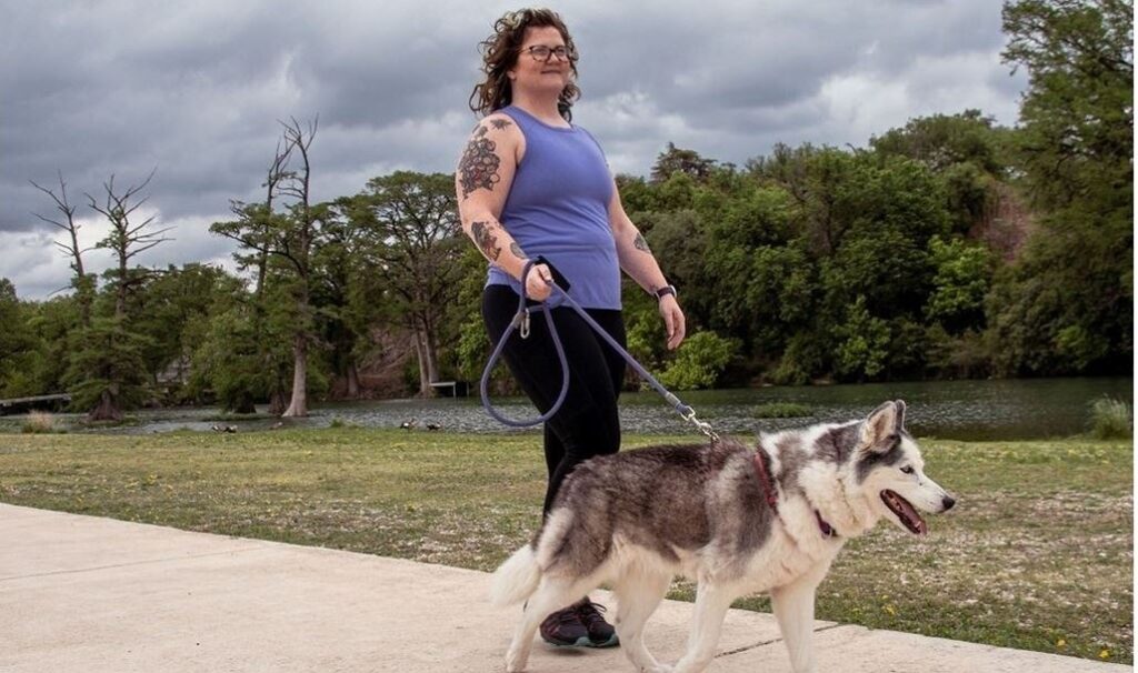 Woman walking dog along river path