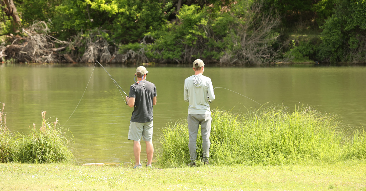 Two men fishing on river bank