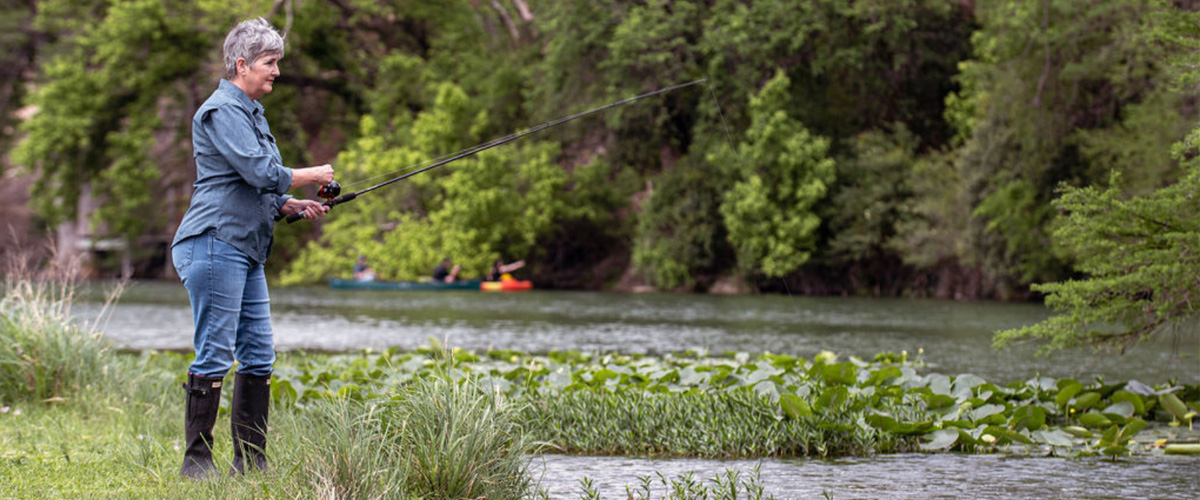 woman fishing on river bank