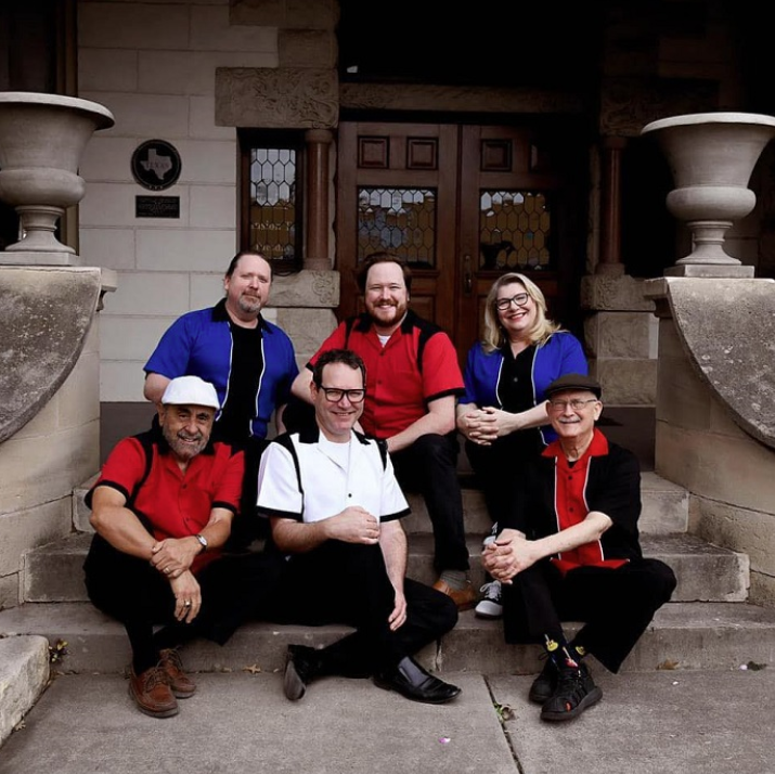 Buddy Holly tribute band posing on stone steps in colorful retro outfits.
