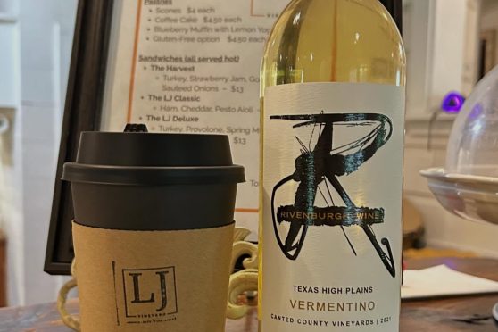 A bottle of LJ Vineyard Vermentino wine next to a branded LJ coffee cup in front of a menu.