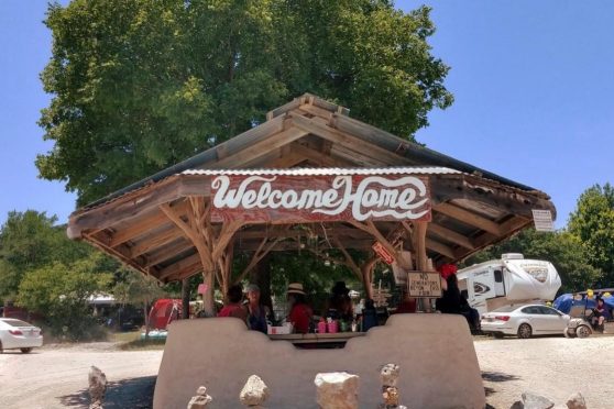 The "Welcome Home" entrance kiosk at the Kerrville Folk Festival under a bright blue sky.