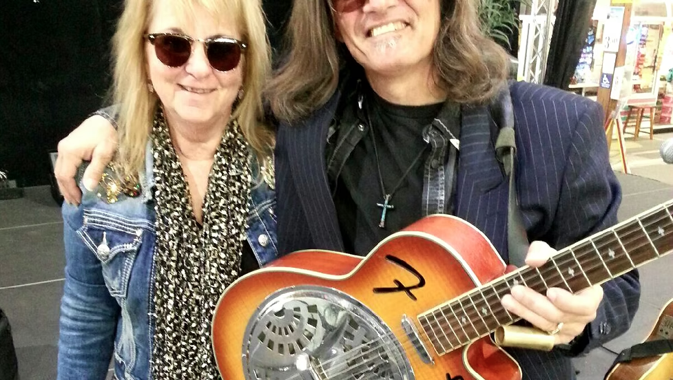 Musicians Danny Brooks and Lil Miss Debi posing together, with Danny holding a resonator guitar.