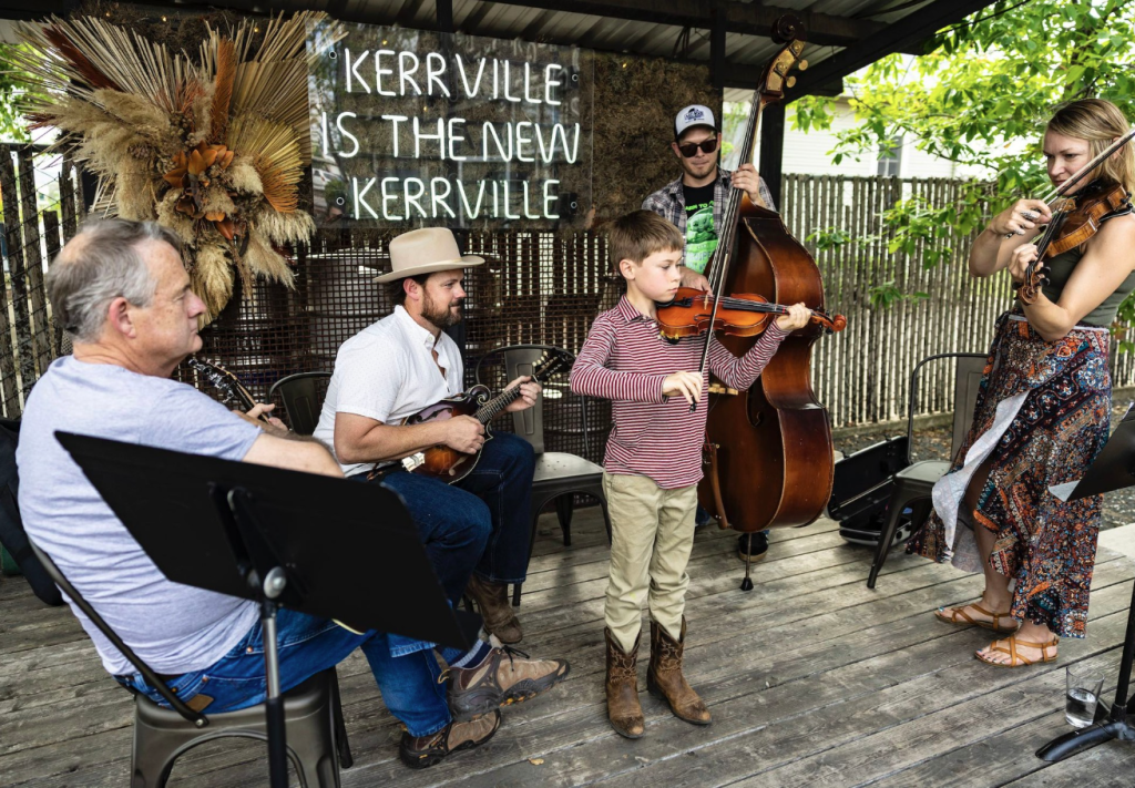 A group of musicians, including a child playing violin, performing "Theresa's Fiddle Jam."